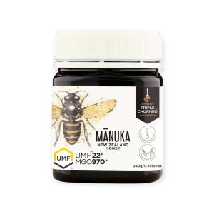Tegla Manuka med UMF 22+ sa tamnijom, gustom teksturom, postavljena uz drvenu kašiku i prirodne dekoracije u rustičnom ambijentu.